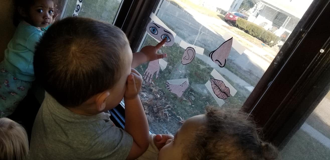 Child pointing at body part cutouts on a window