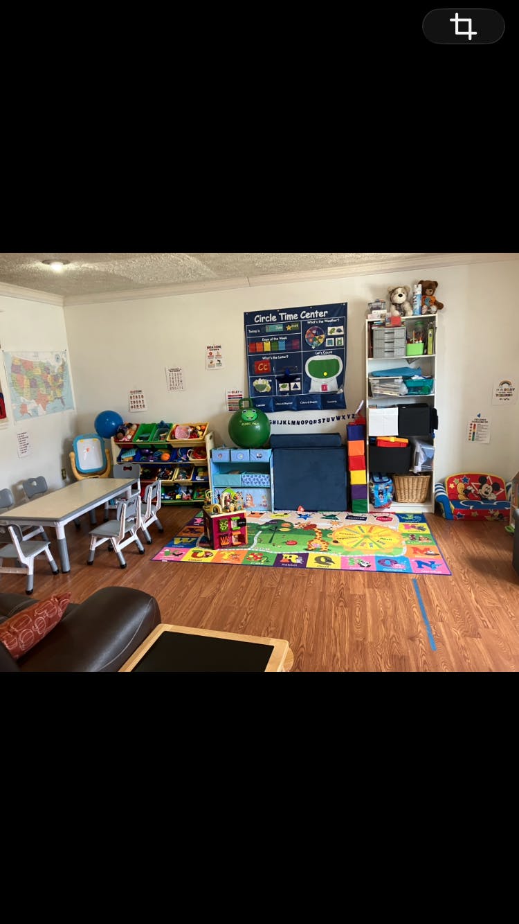 Children's play area with a colorful rug, activity board, and small table and chairs