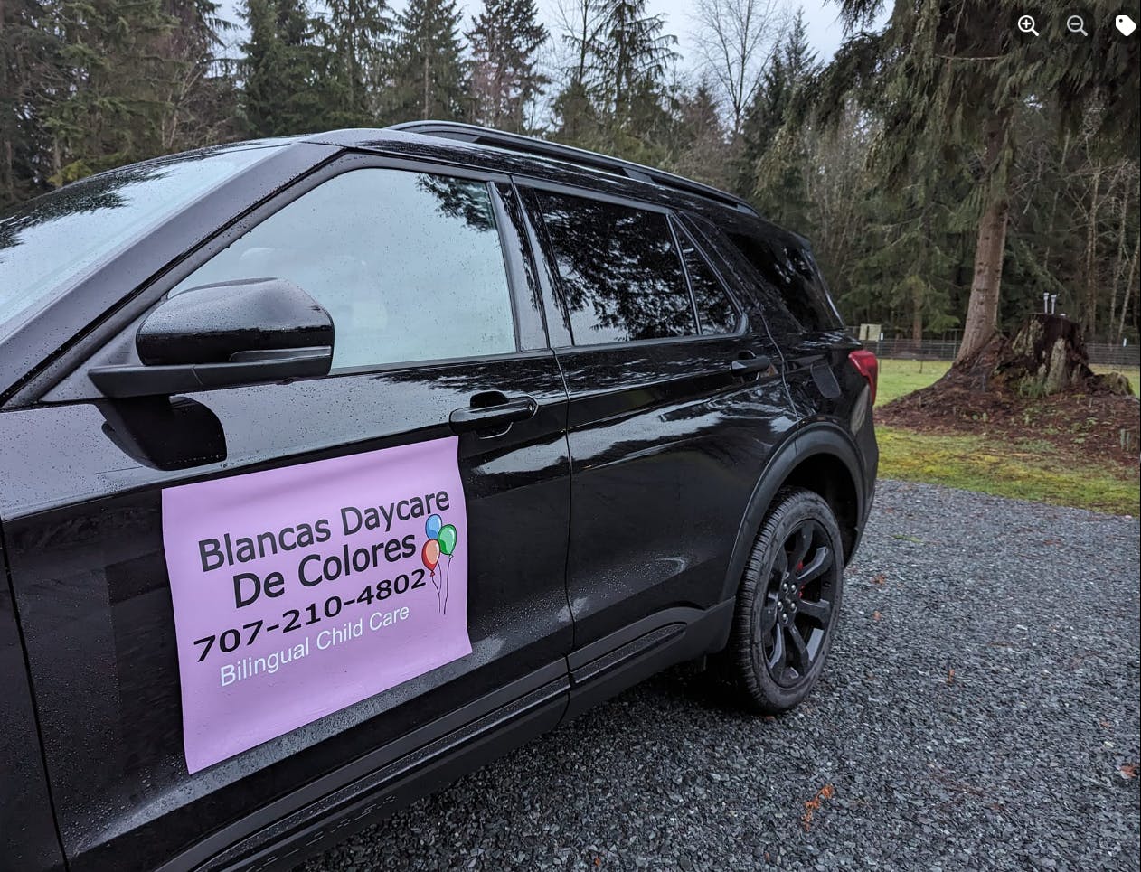 Black car with a pink sign that reads "Blancas Daycare De Colores"