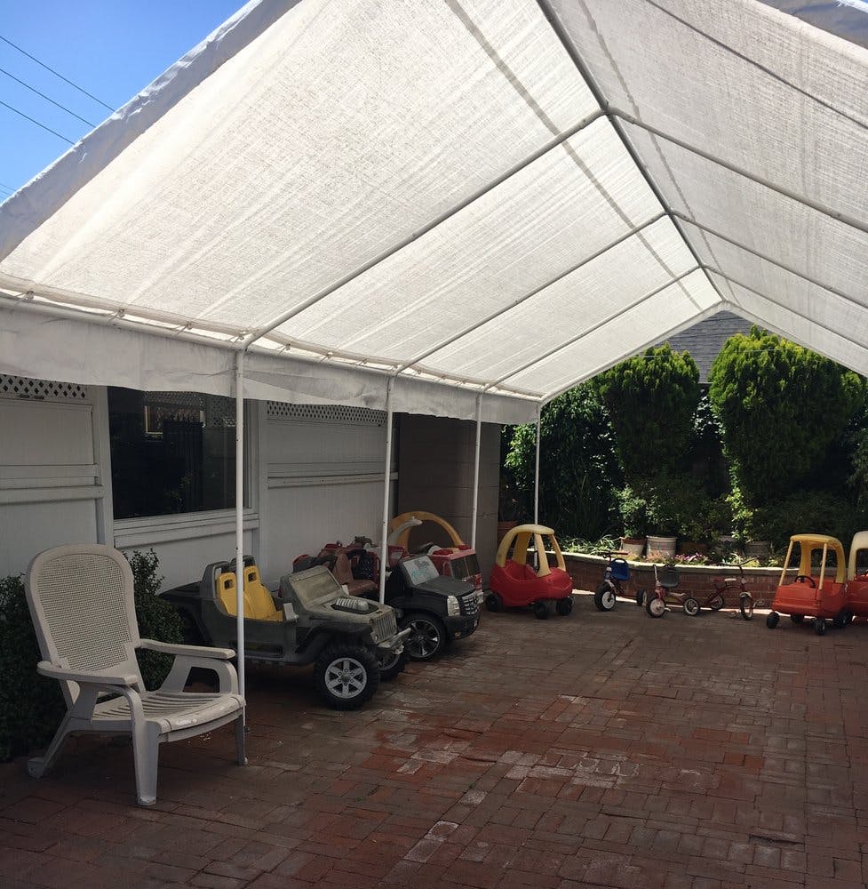 White canopy tent over a patio with toy cars and a white chair