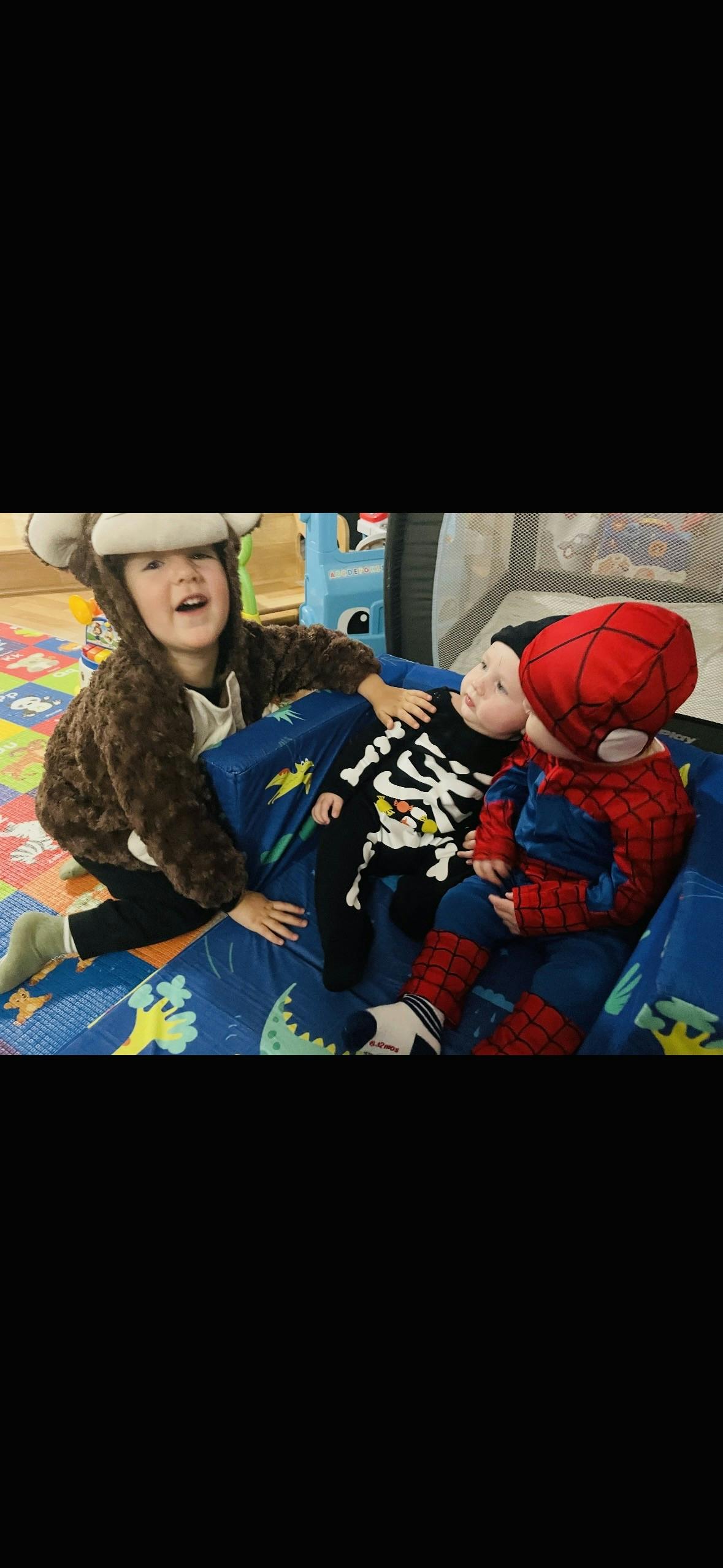 Three children in costume, one in a monkey suit, one in a skeleton suit, and one in a Spiderman suit