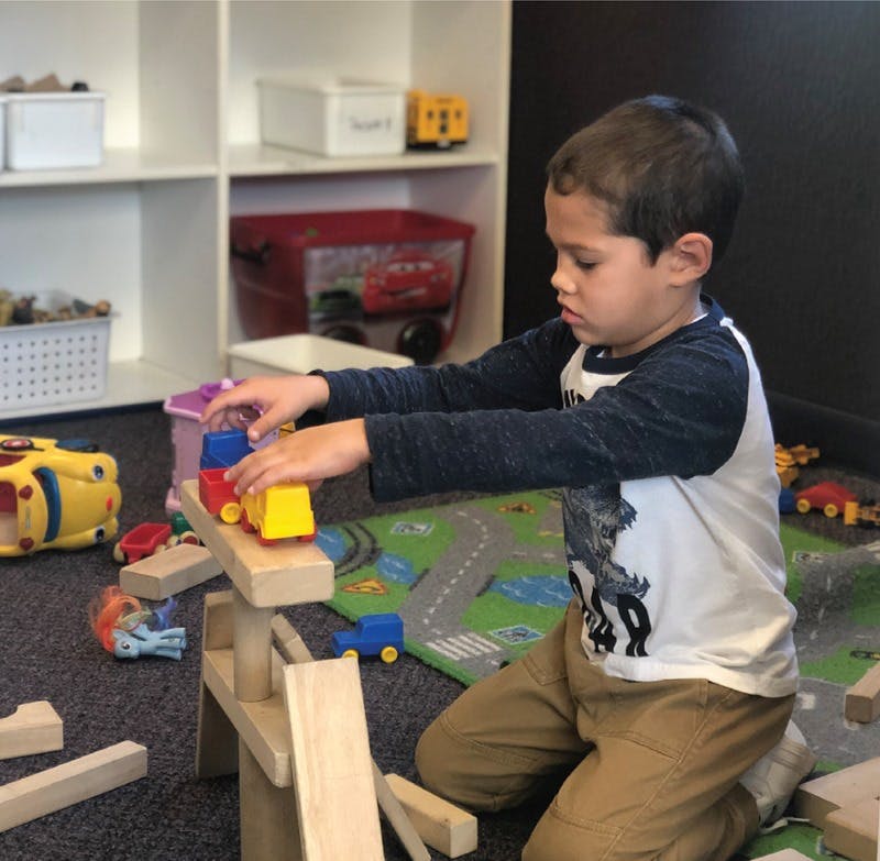 Child playing with toy cars and wooden blocks