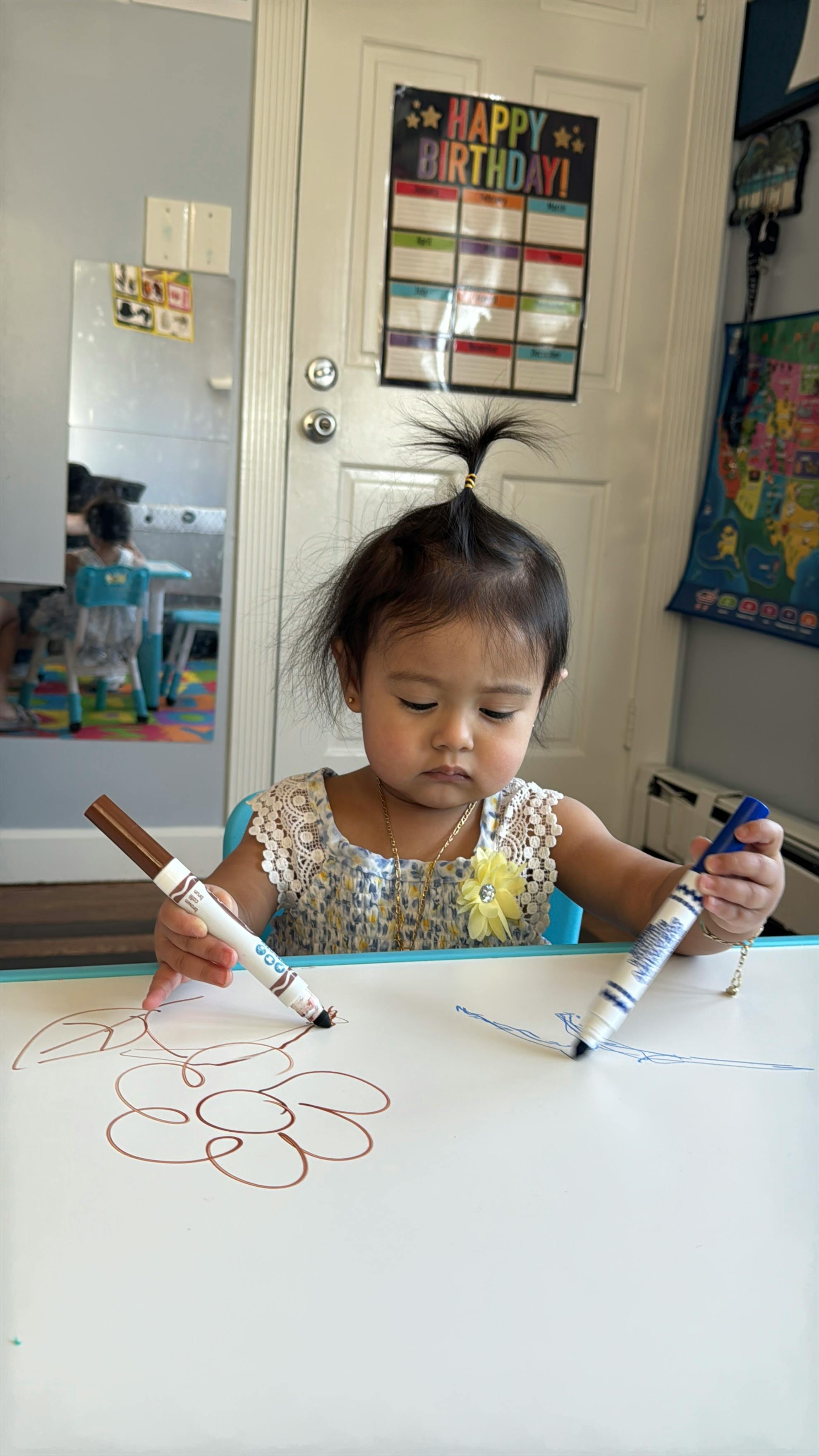 Child drawing on a whiteboard with markers