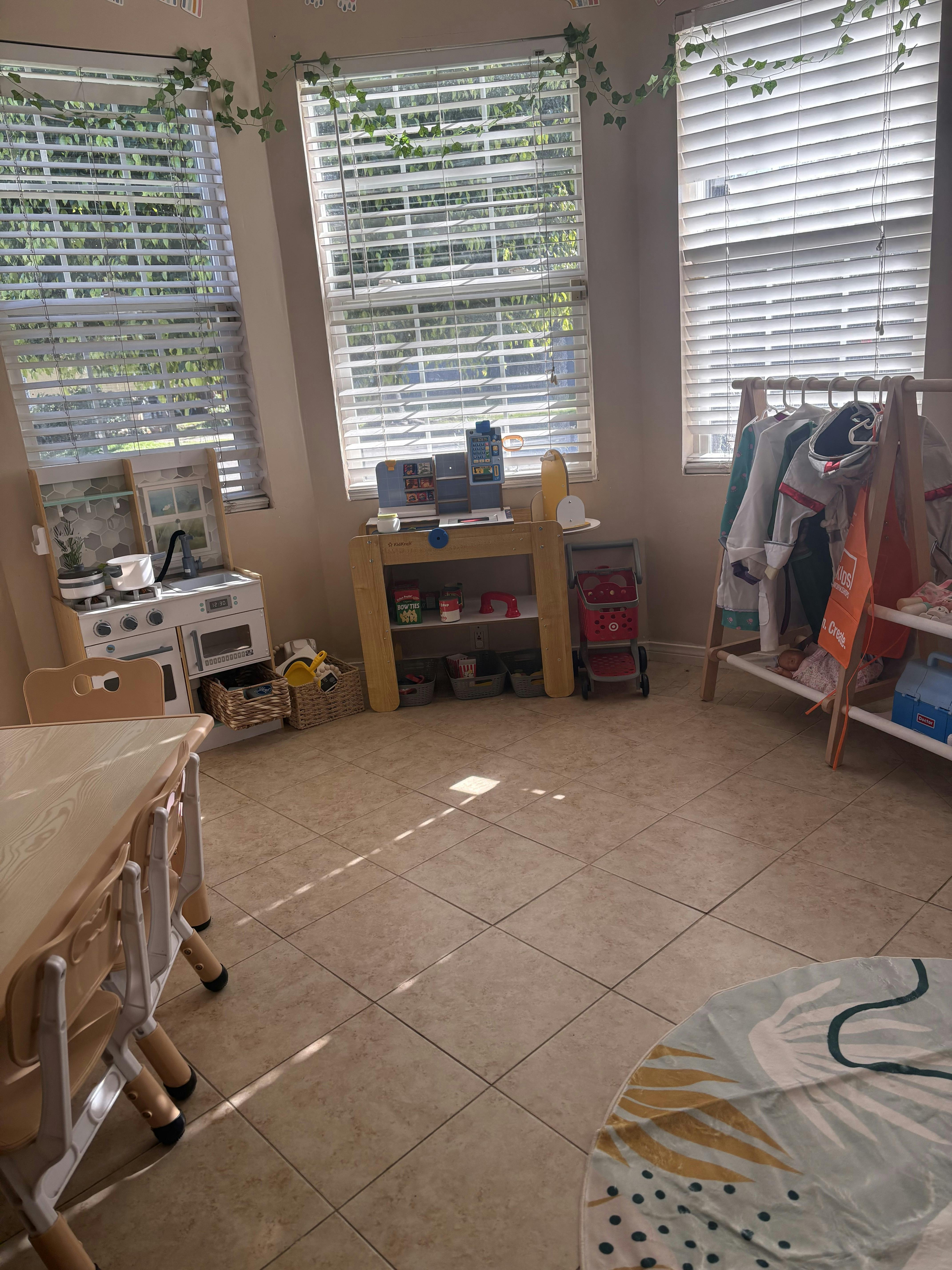 Play kitchen and wooden rack with costumes in a room with windows