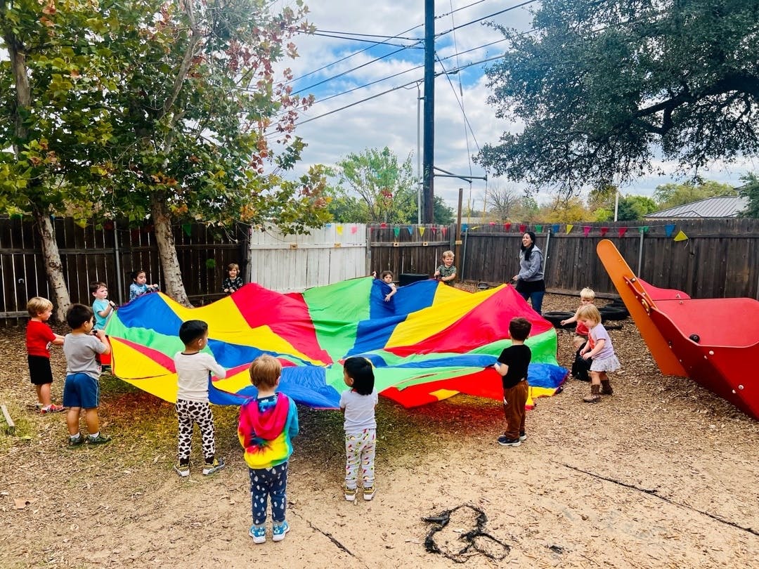 Children and adults playing with a colorful parachute outdoors