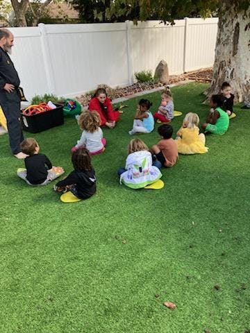 Adult and children sitting on grass in a circle