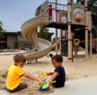Two children playing in sand with toys at a playground