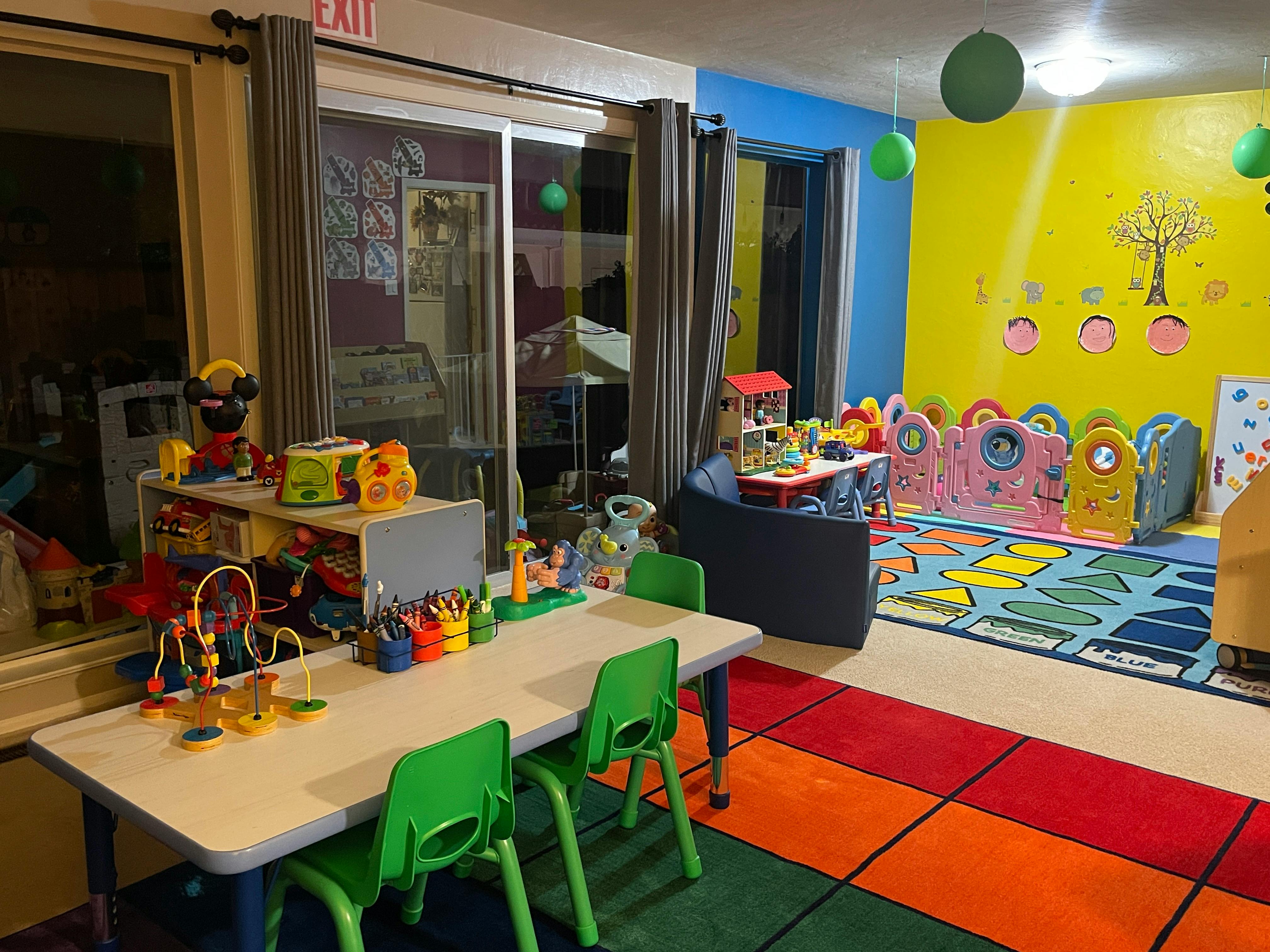 Playroom with small tables and chairs, colorful rug, and toys