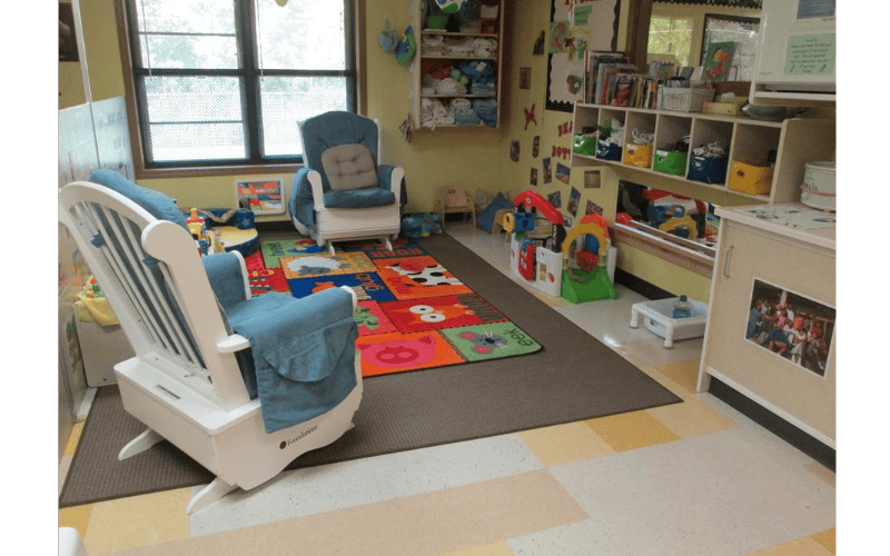Classroom with two rocking chairs, an alphabet rug, and toys