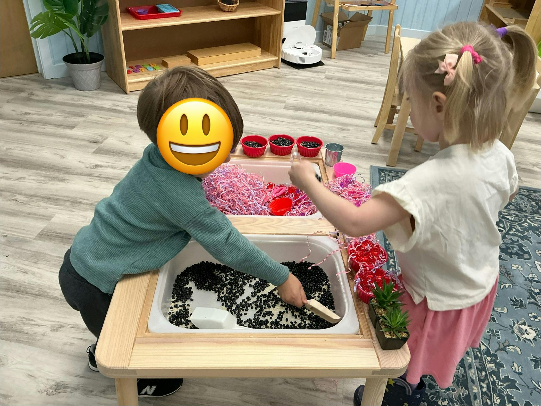Two children playing at a sensory table with various materials