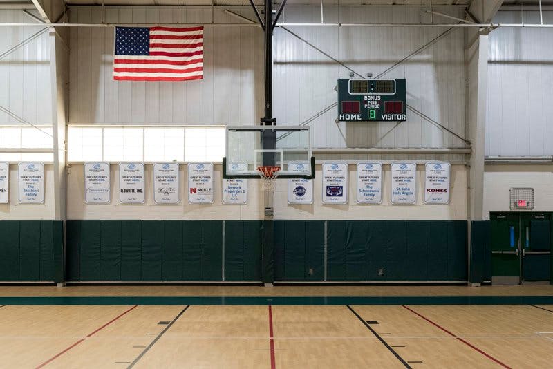 Empty basketball court with a scoreboard and American flag