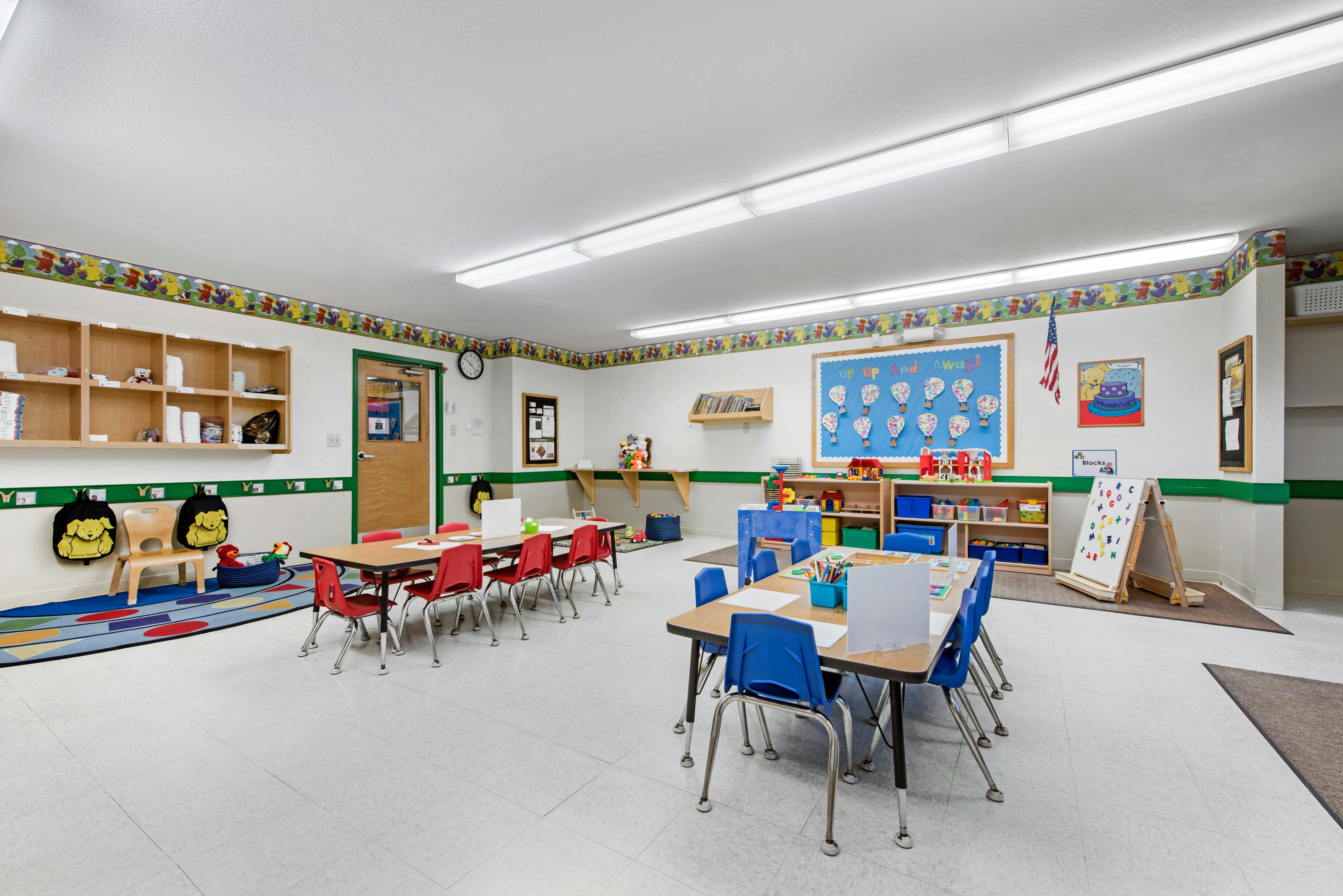 An empty classroom with several small tables and chairs