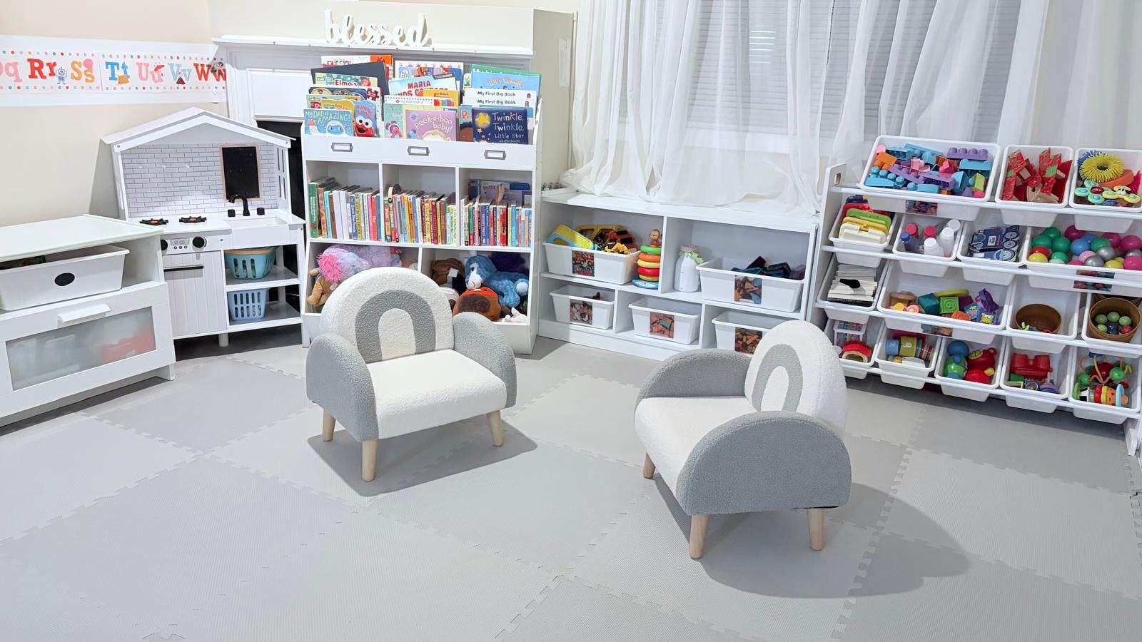 Children's play area with toy kitchen, bookshelves, toy organizers, and two small chairs