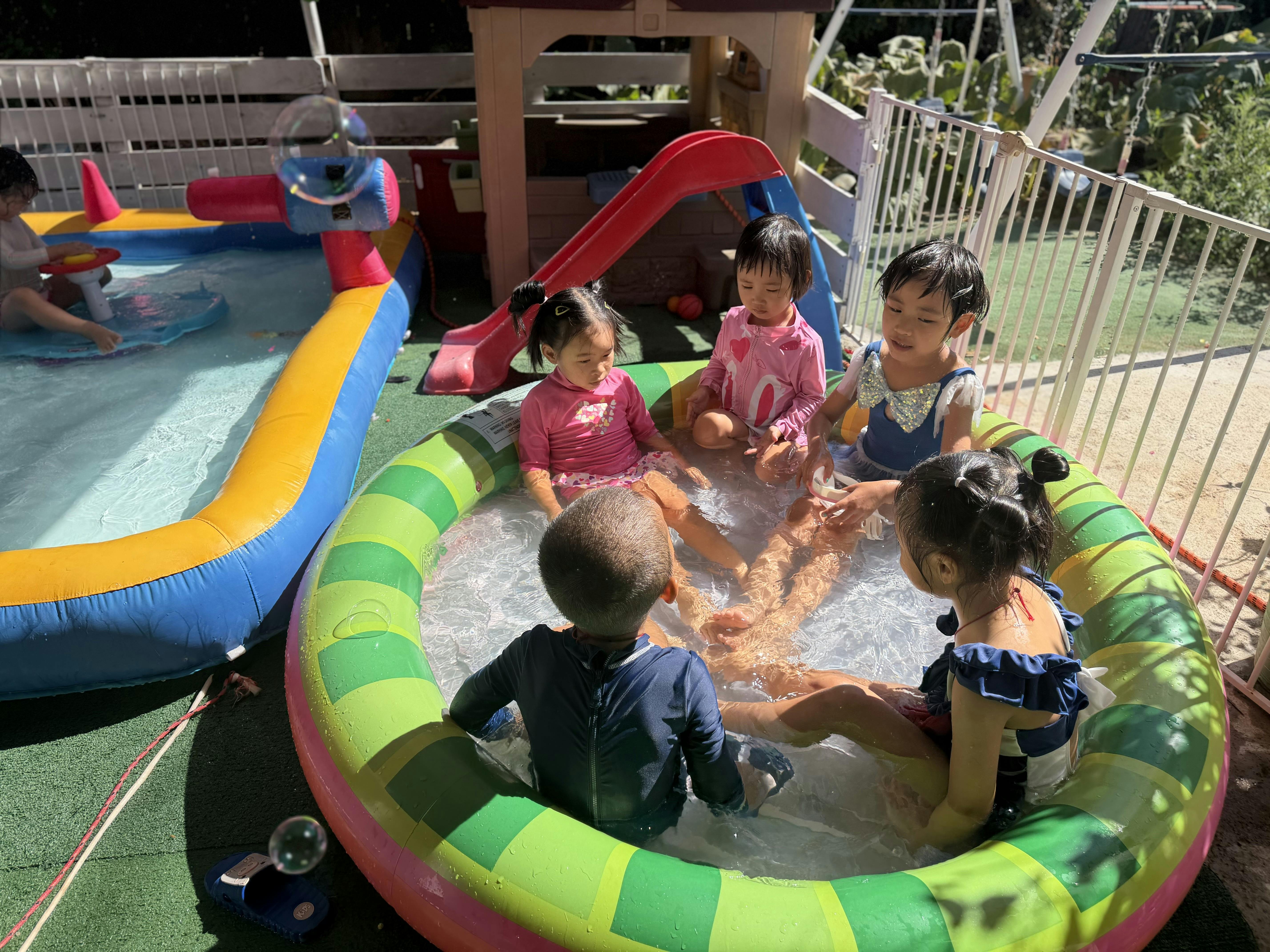 Group of children playing together in a small circular inflatable pool