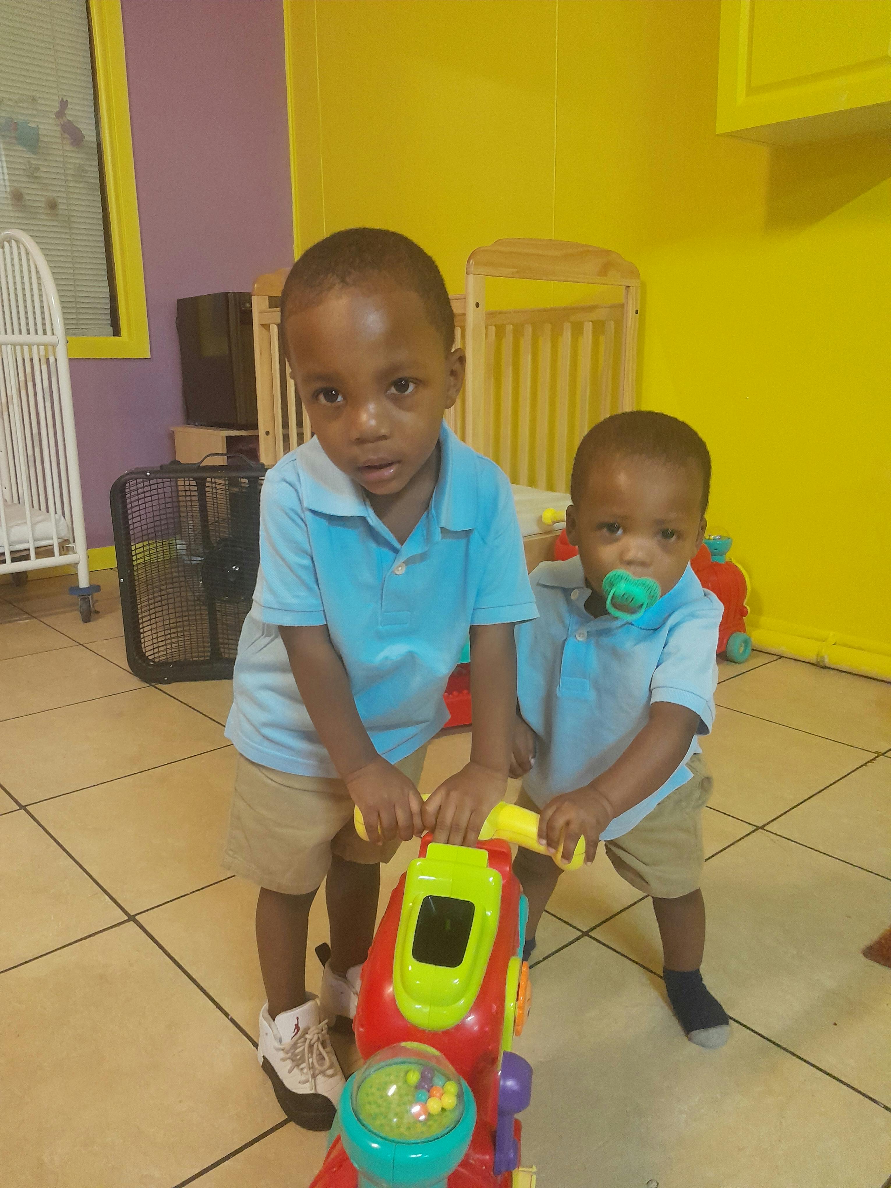 Two children standing with a toy
