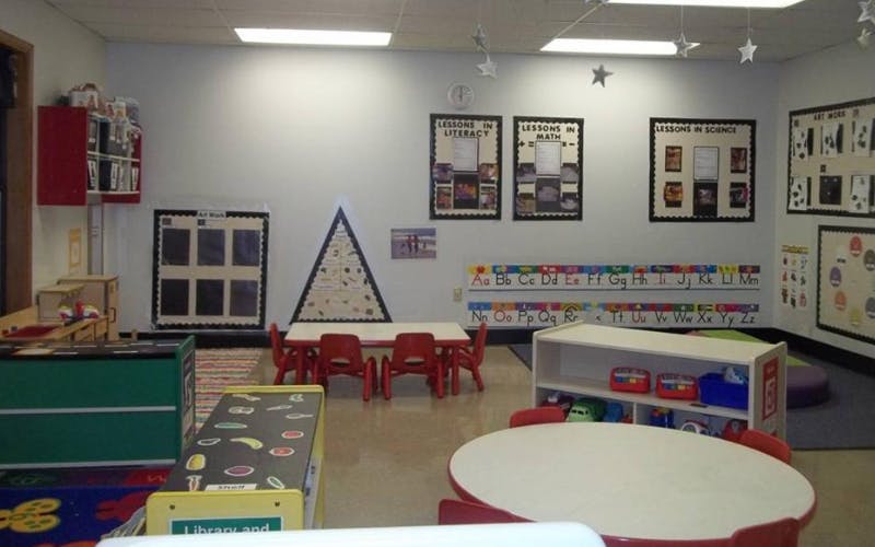 Classroom with child-sized tables and chairs, posters, and learning materials on walls