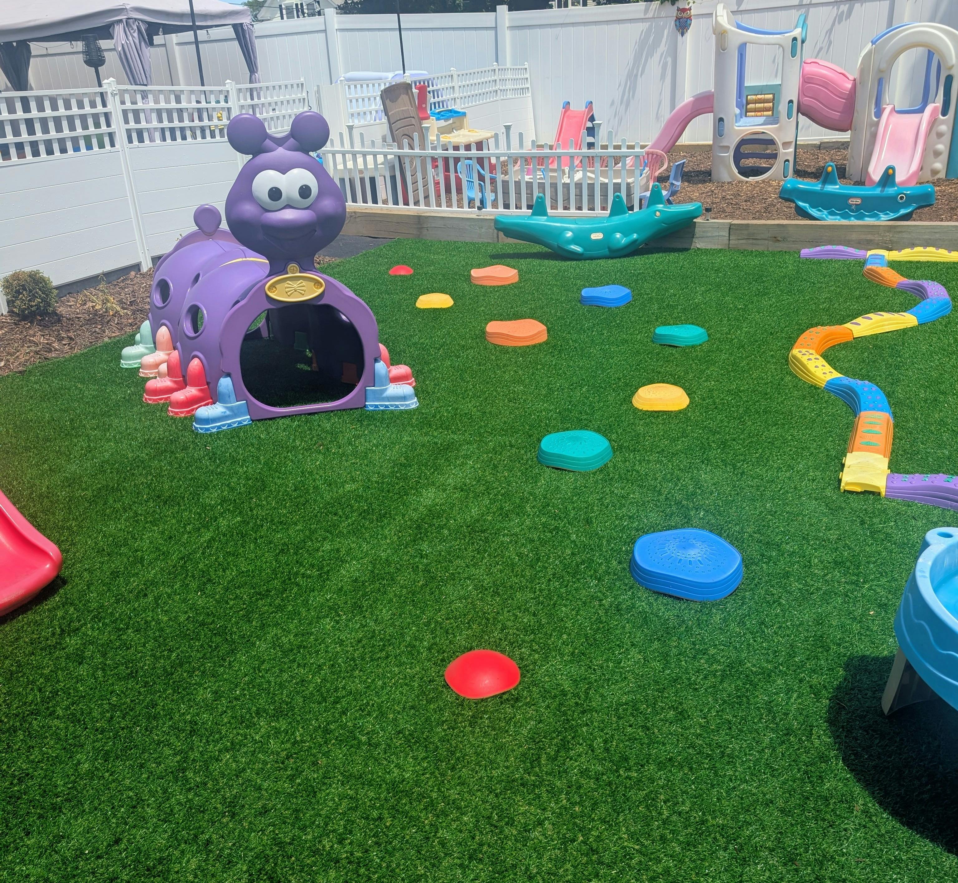 Outdoor playground with purple caterpillar tunnel and colorful stepping stones