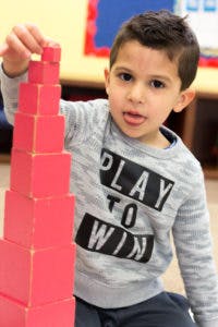 Child stacking red blocks