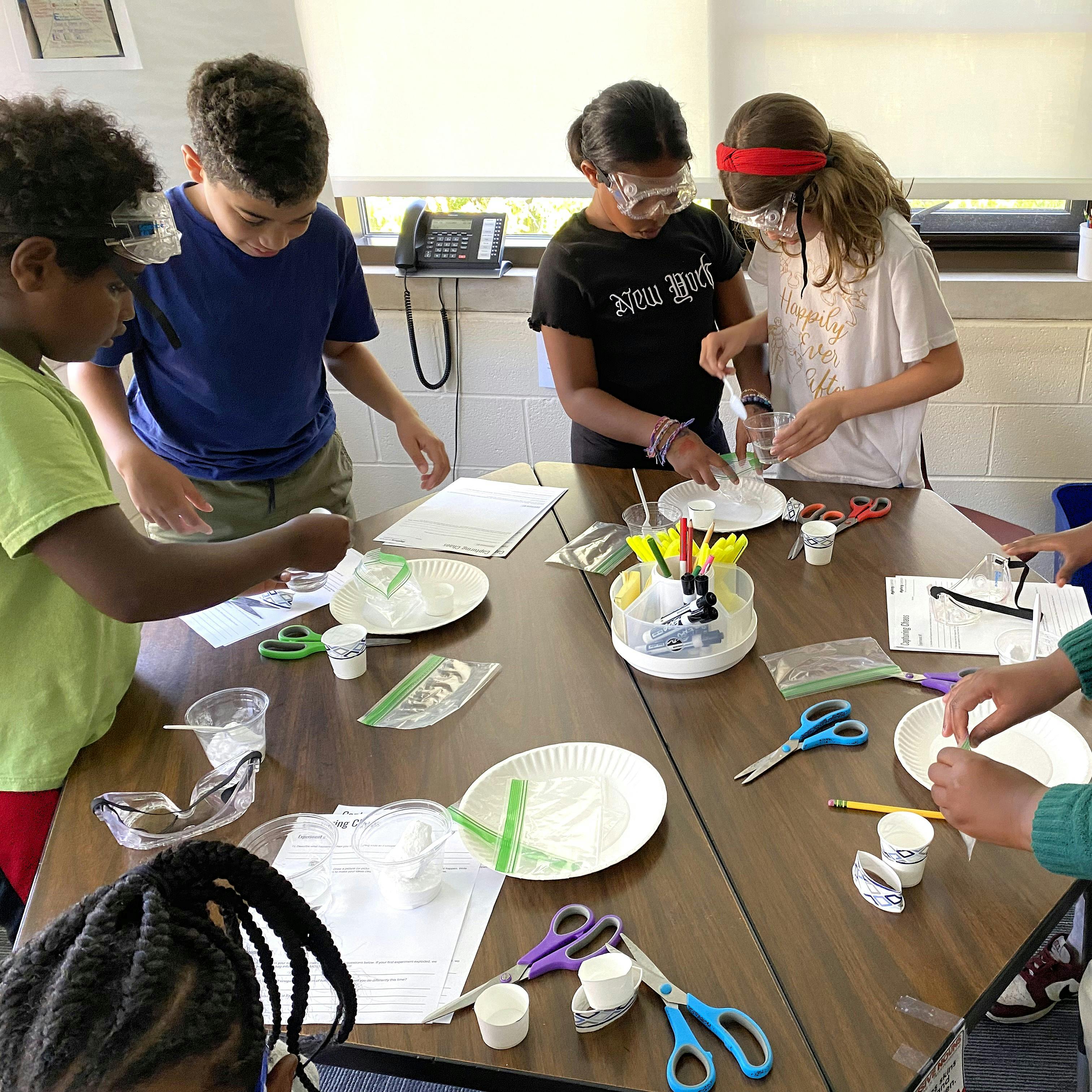 Children wearing safety goggles doing an activity at a table