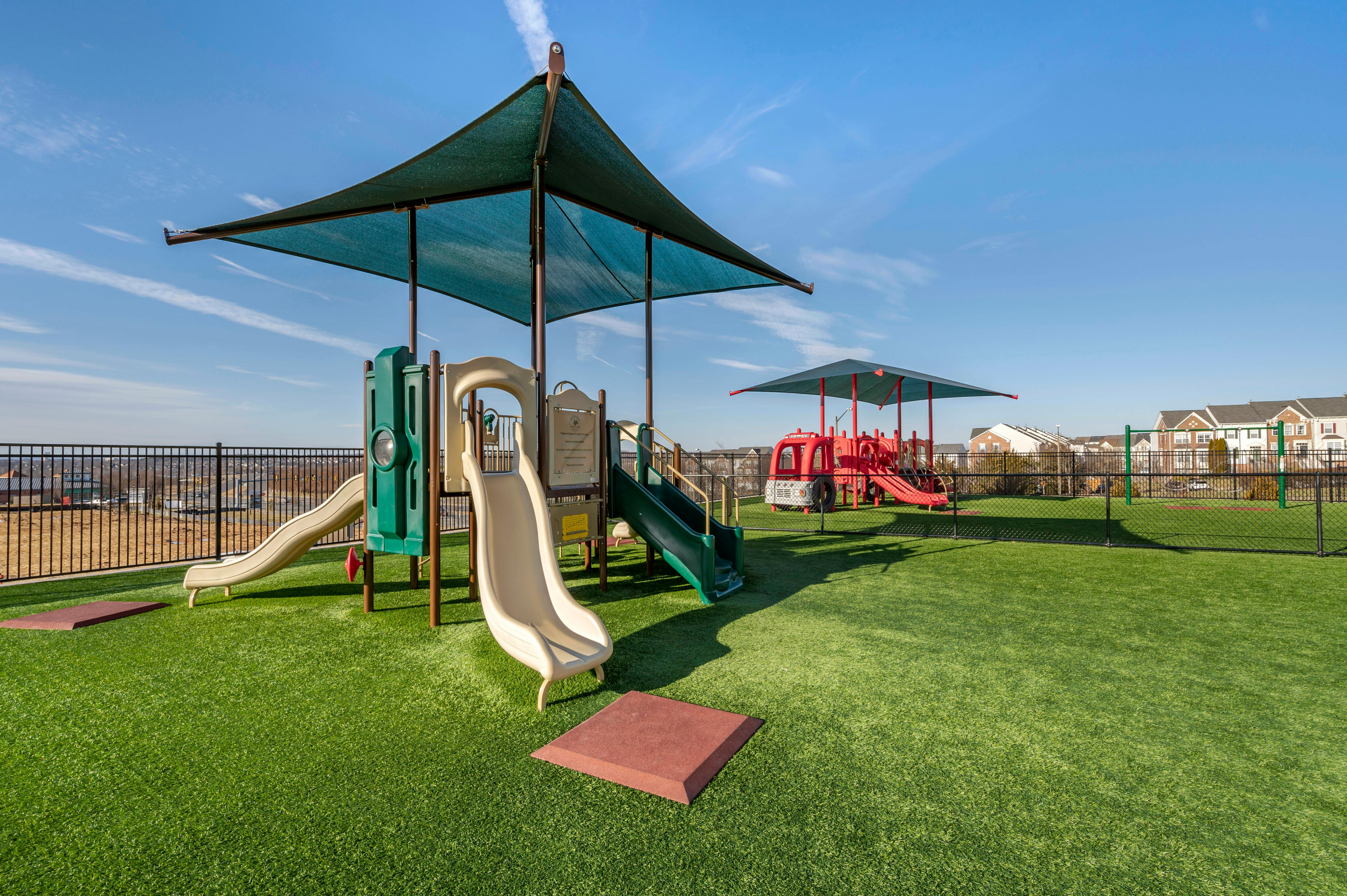 Playground with green turf, slides, and shaded structures