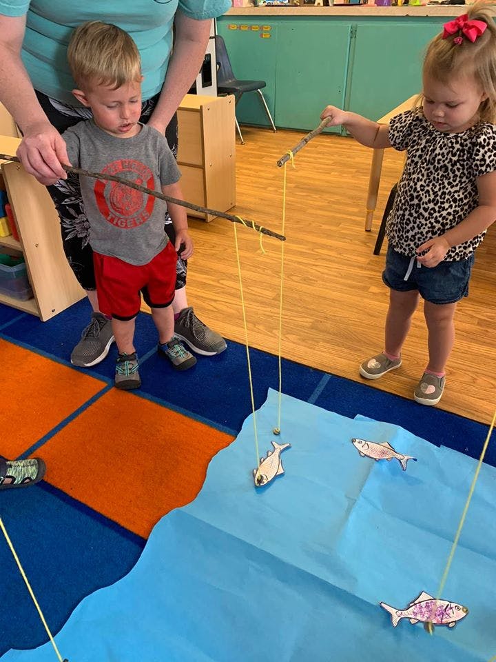 Adult and two children playing a fishing game with paper fish