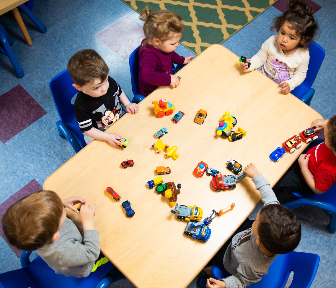 Children playing with toy cars at a table