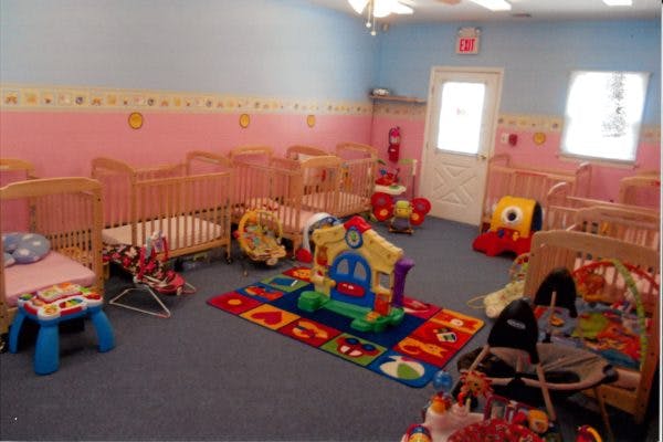 Nursery room with multiple cribs, play mat, and toys