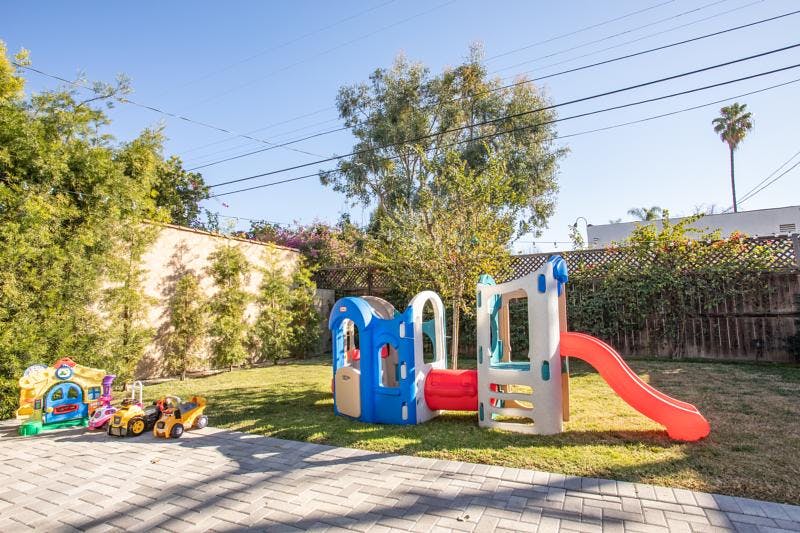 Children's play structure with slide and toy vehicles in a backyard