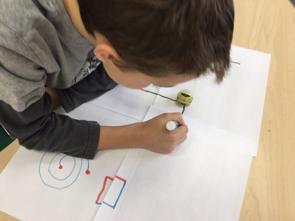 Child drawing on paper with a small toy car