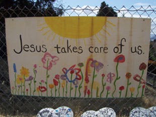 Hand-painted sign with text "Jesus takes care of us." and flowers