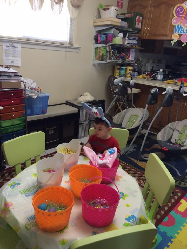 Child wearing bunny ears sitting at a table with Easter baskets