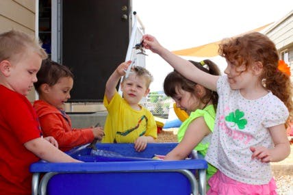 Children playing with water in a blue bin