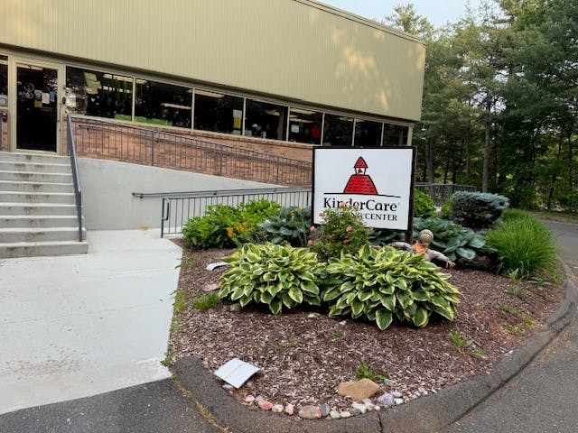 KinderCare sign in a landscaped area next to a building entrance