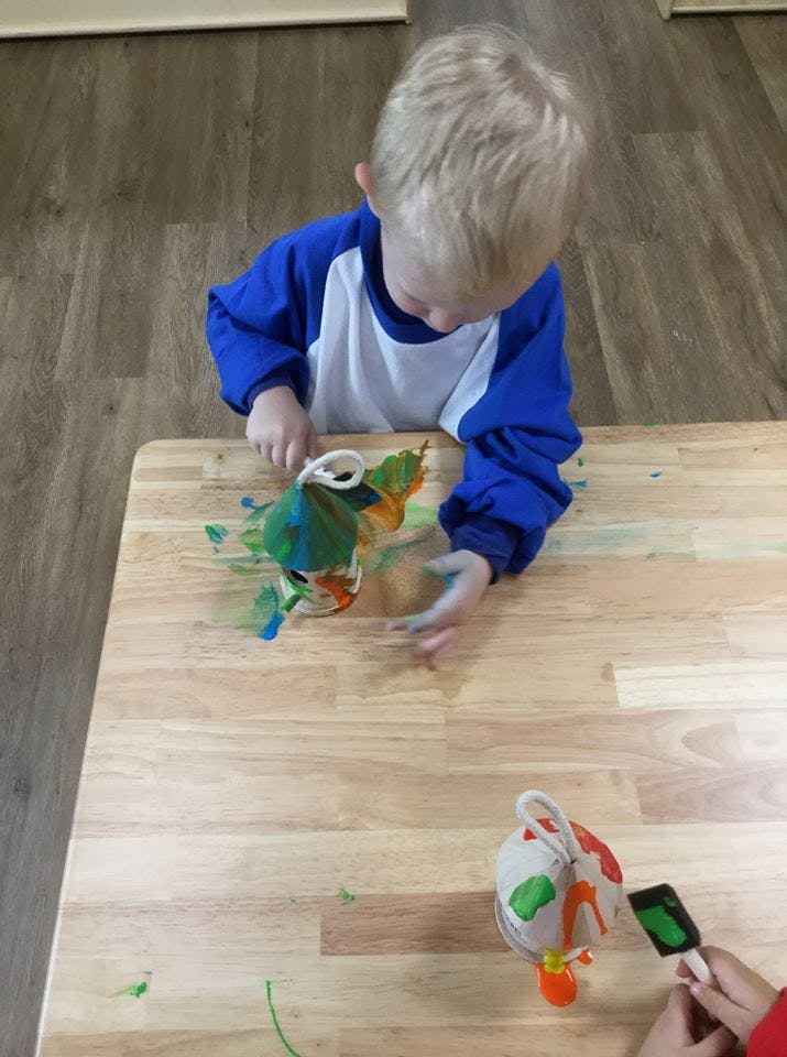Child painting a craft on a wooden table