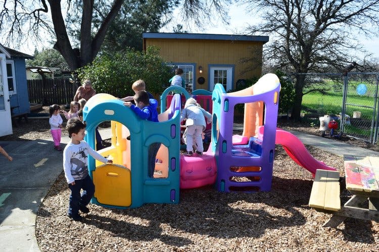 Children playing on a colorful playground structure with a slide