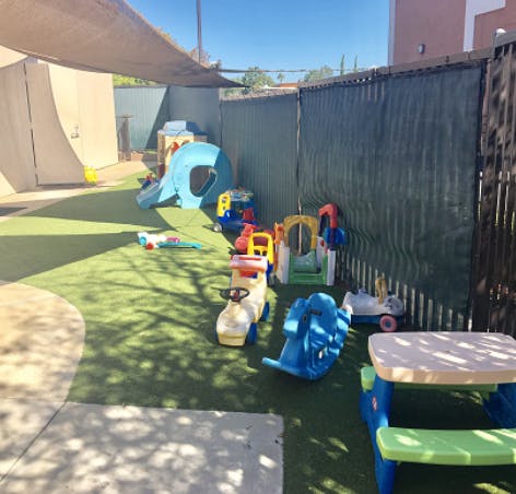 Outdoor play area with various colorful toys on artificial turf