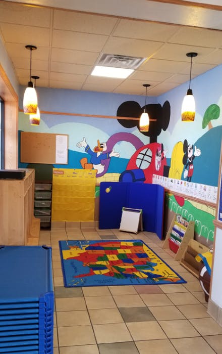 Children's play area with a US map rug and cartoon murals
