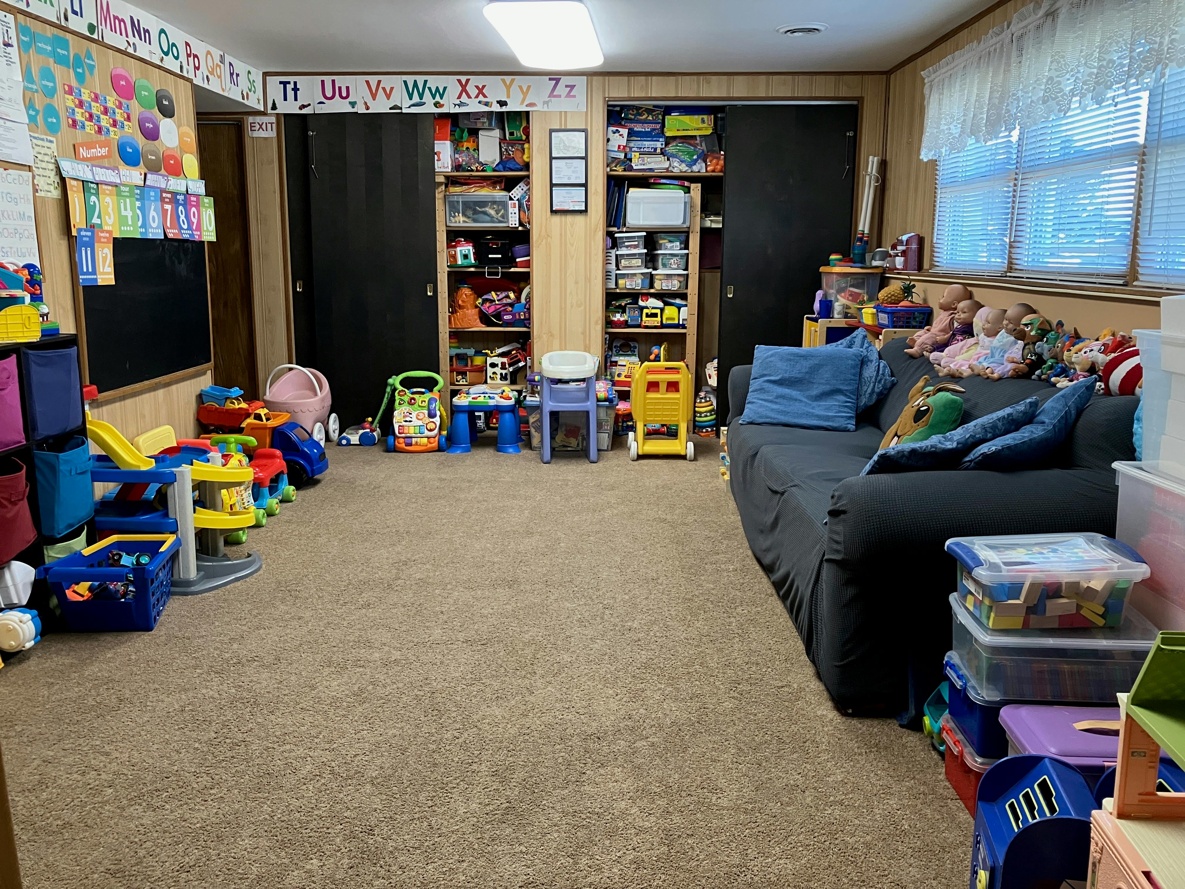 Playroom with toys, shelves, and a dark sofa
