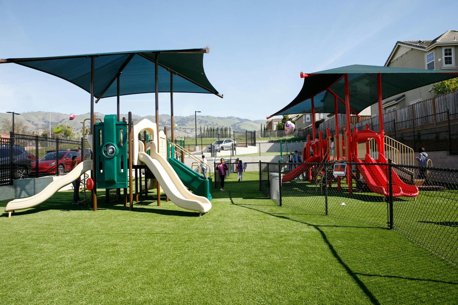Playground with multiple slides and shade structures on artificial turf