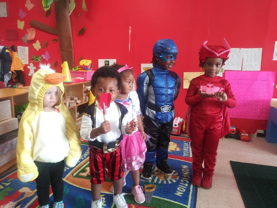 Four children in costumes, including a duck, pirate, blue superhero, and red superhero