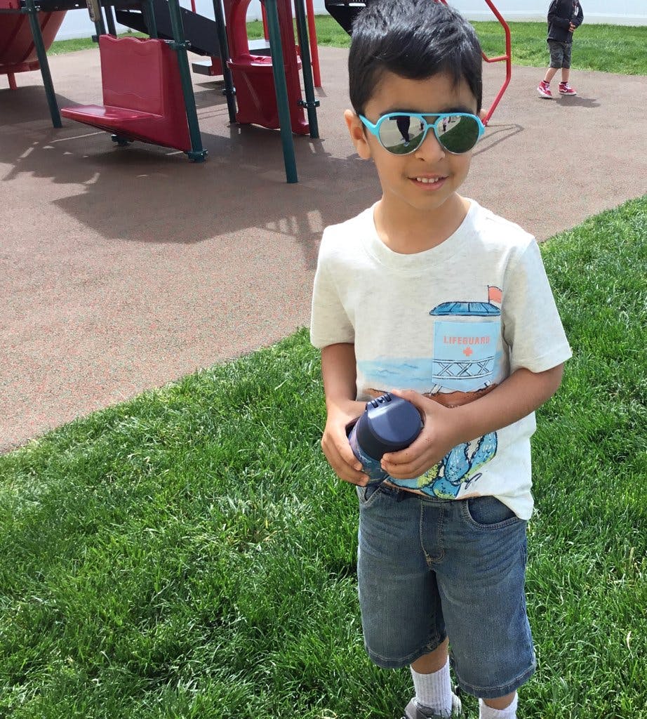 Child wearing sunglasses and holding a cup on a playground