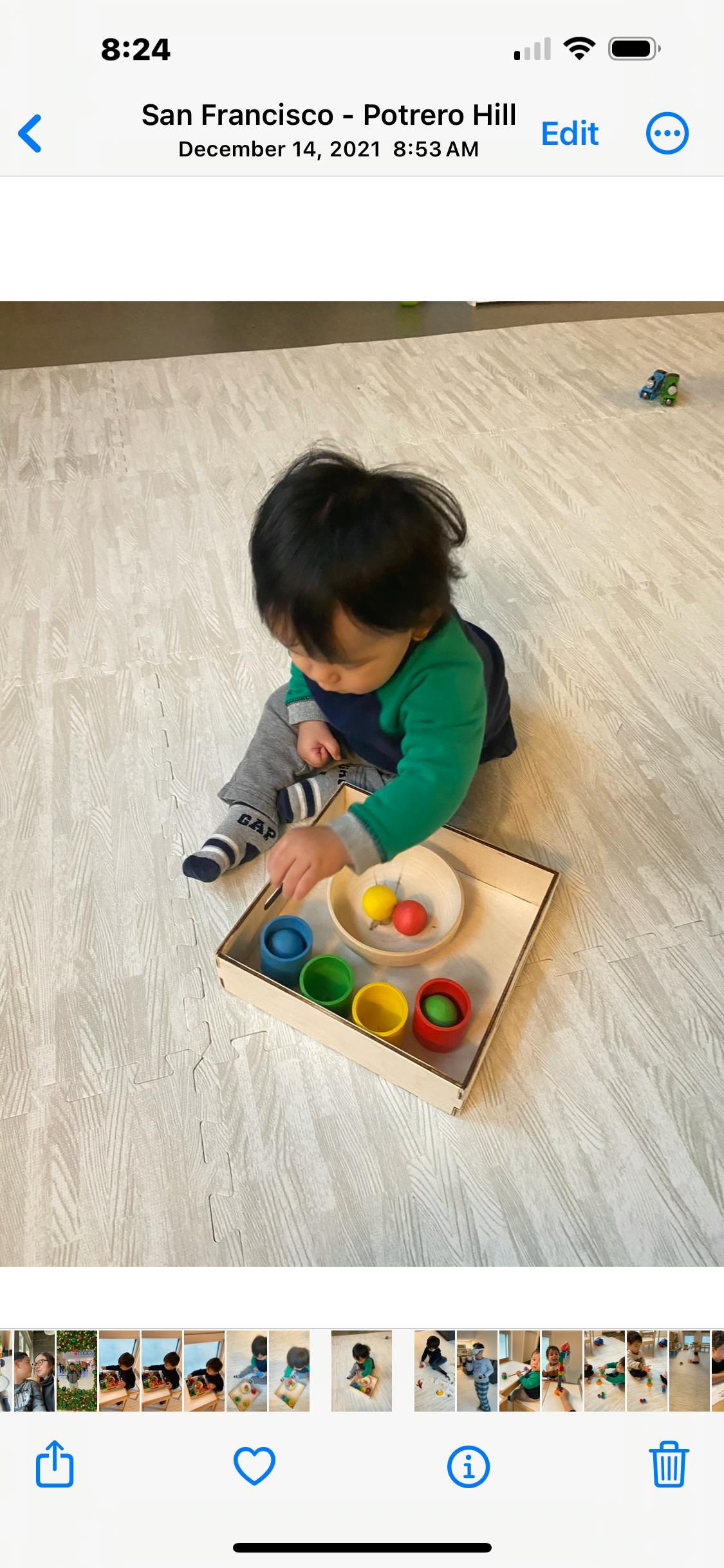 Child playing with colorful cups and balls in a wooden tray