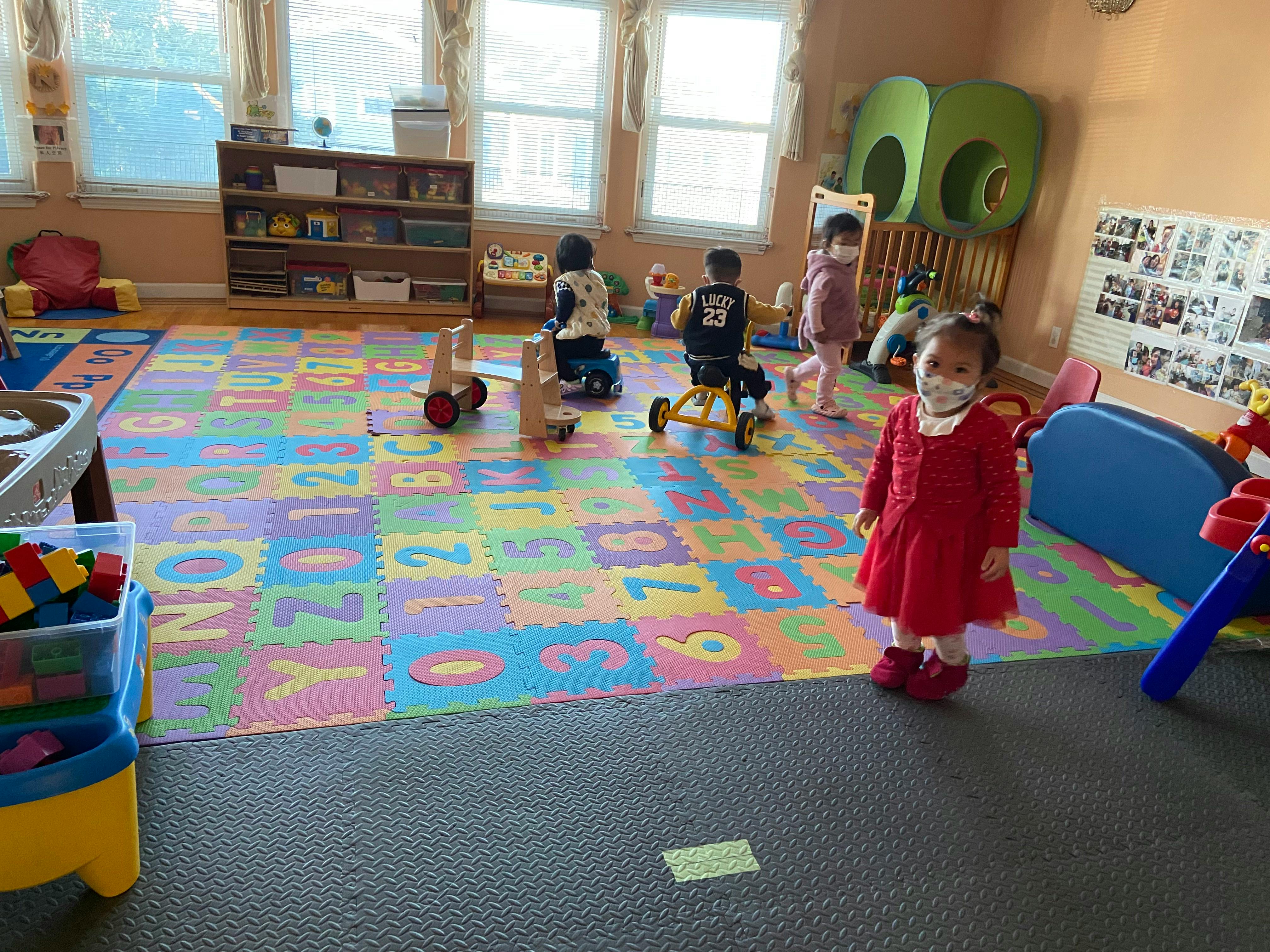 Children playing in a room with a colorful alphabet and number mat
