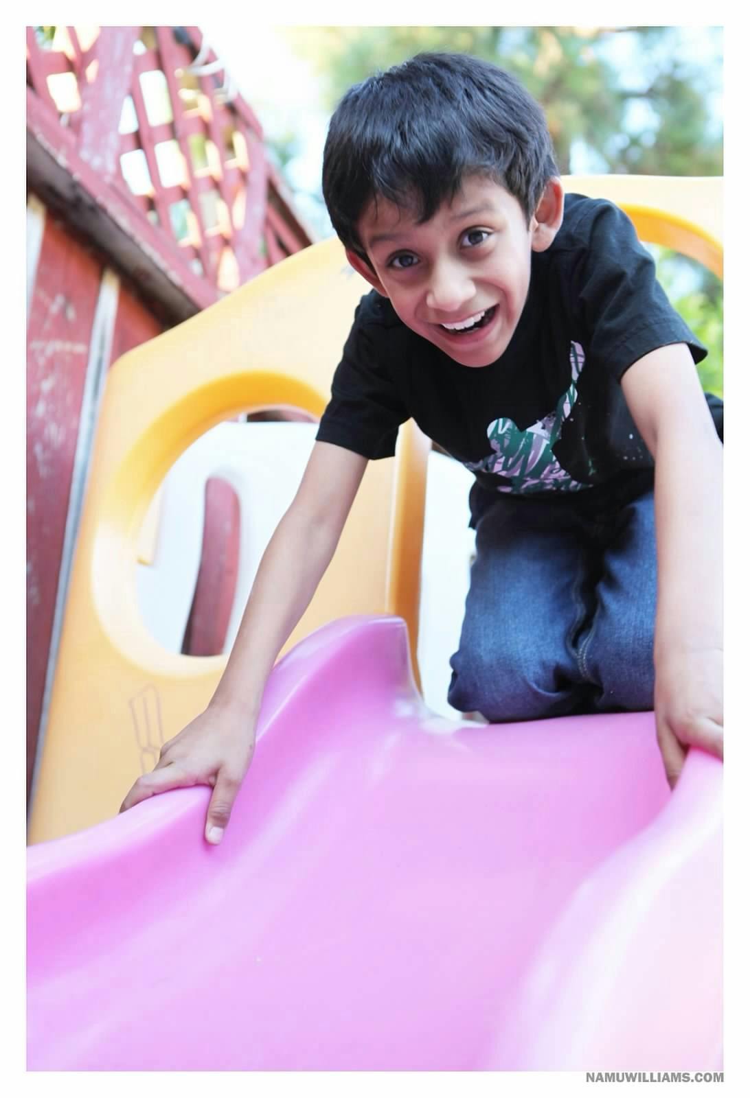 Child on hands and knees on a pink slide