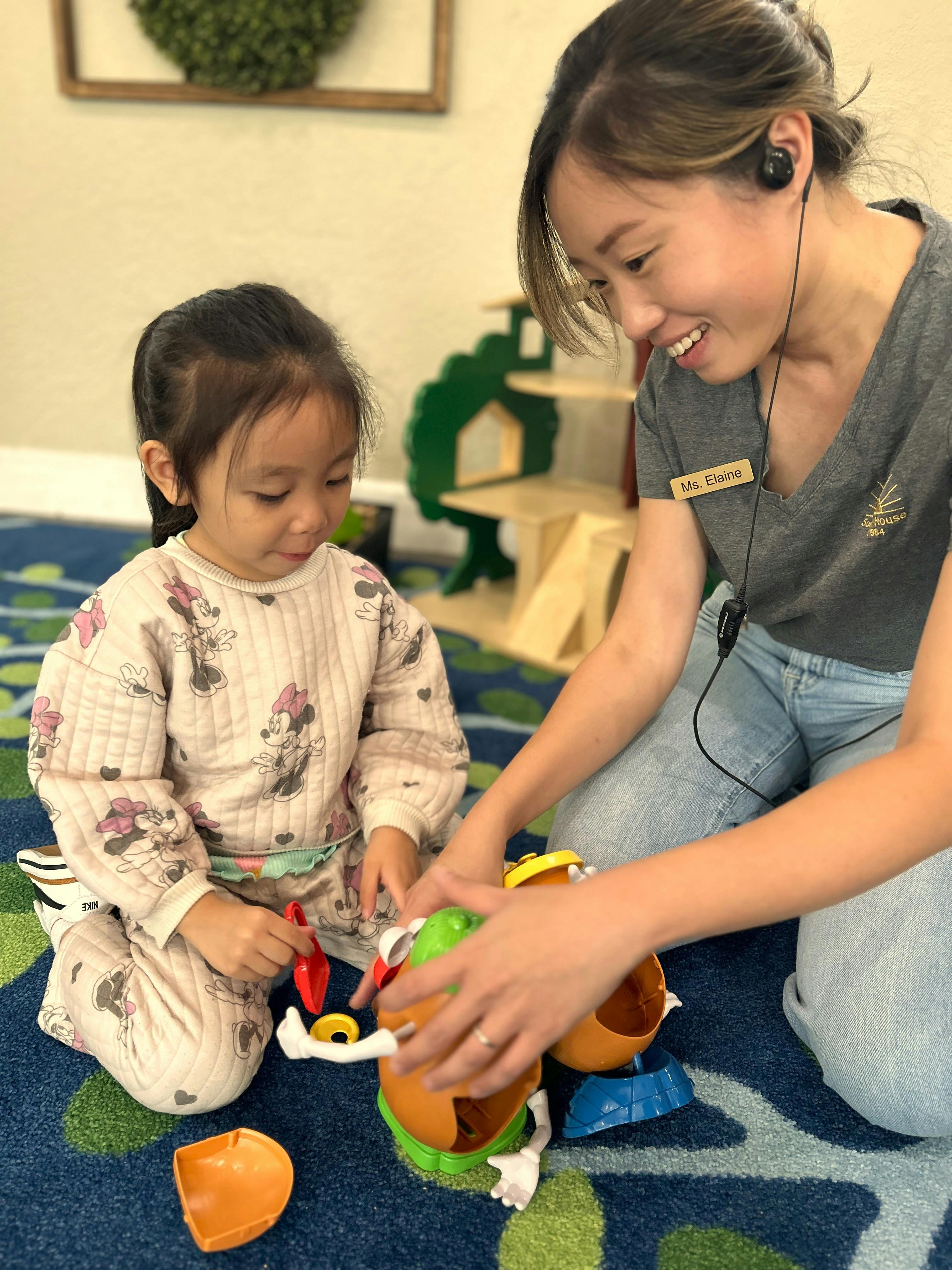 A person and a child playing with a toy on a carpeted floor