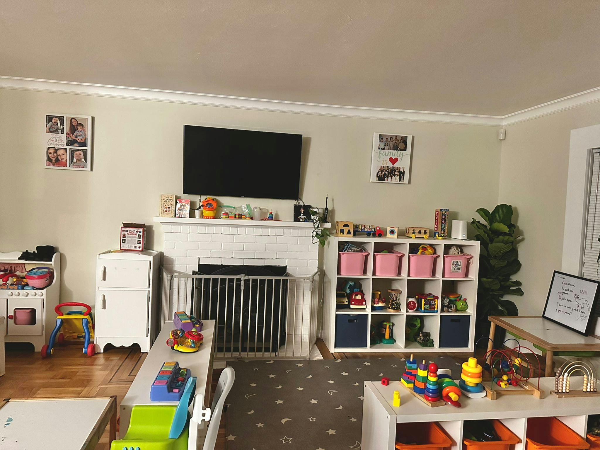 Playroom with toys, shelves, and a television above a fireplace