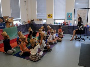 Adult and children sitting on floor in classroom