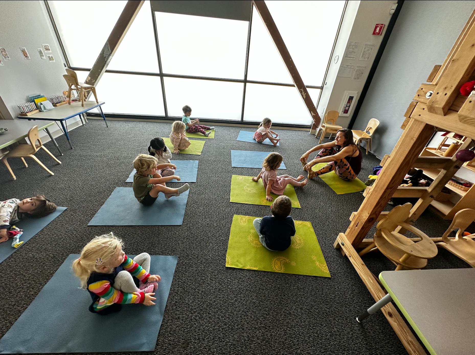 Children and an adult doing yoga on mats in a room
