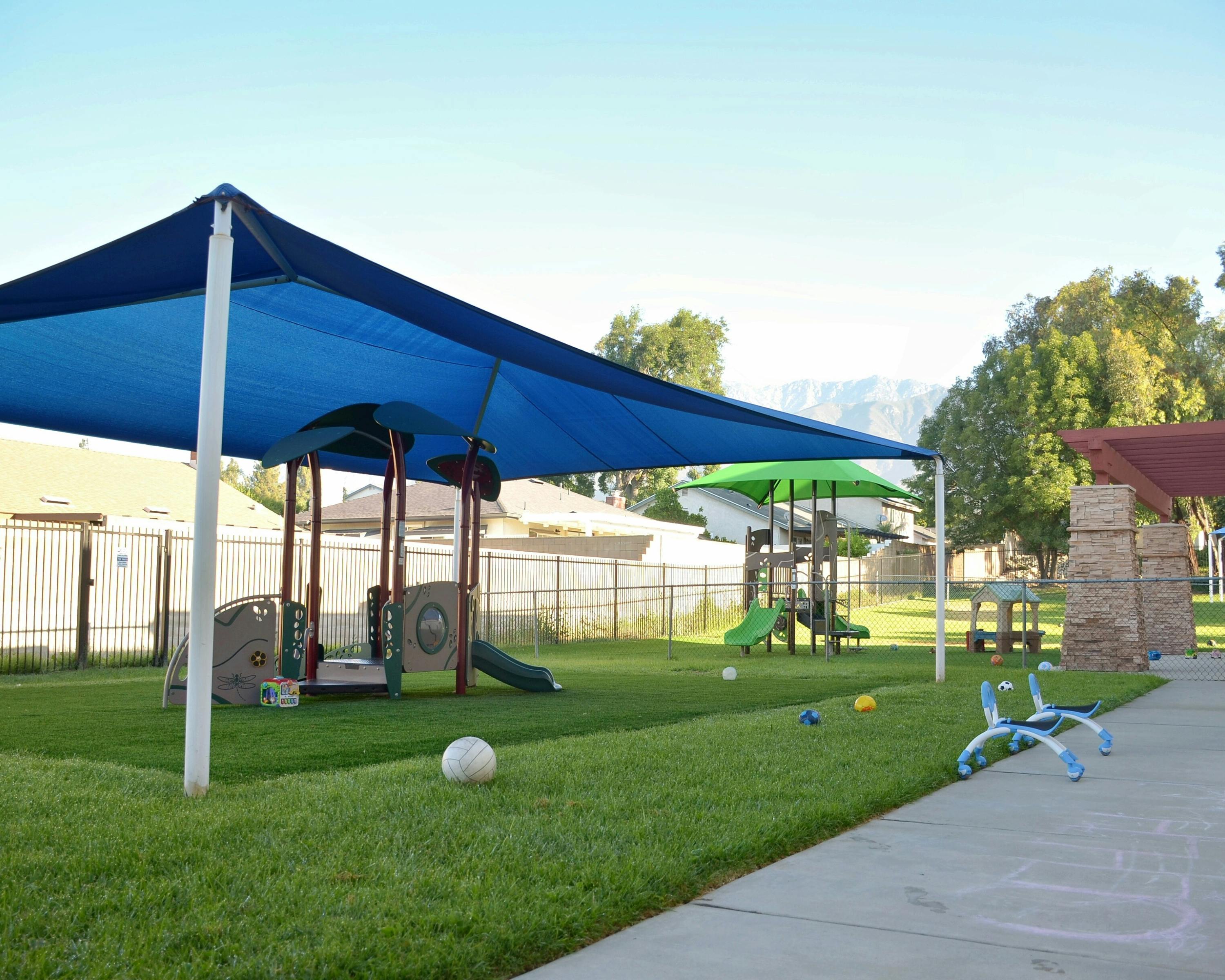 Playground with blue shade structure and play equipment on grass