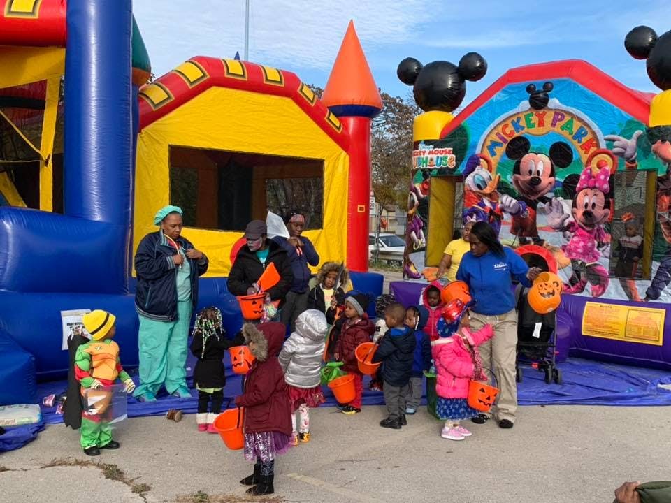 People and children in costumes with buckets near bounce houses